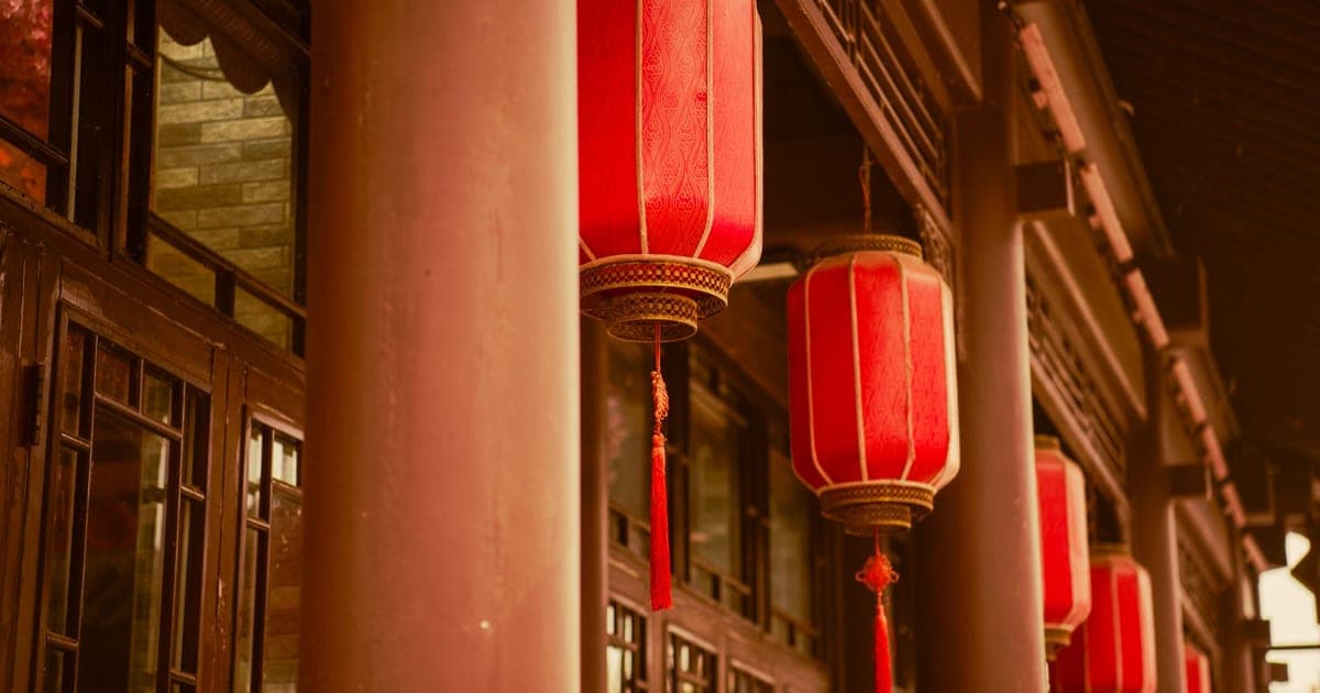 Farolillos rojos con borlas doradas colgados entre las columnas de un edificio tradicional chino