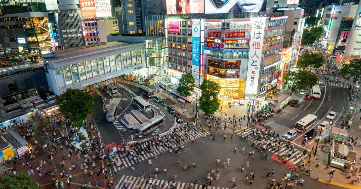 Shibuya Crossing at dusk with neon lights and crowds in Tokyo, Japan