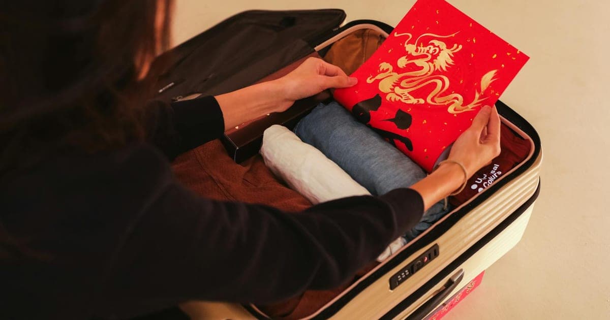 Open suitcase on a bed with neatly organized clothes, packing cubes, and travel essentials laid out beside it