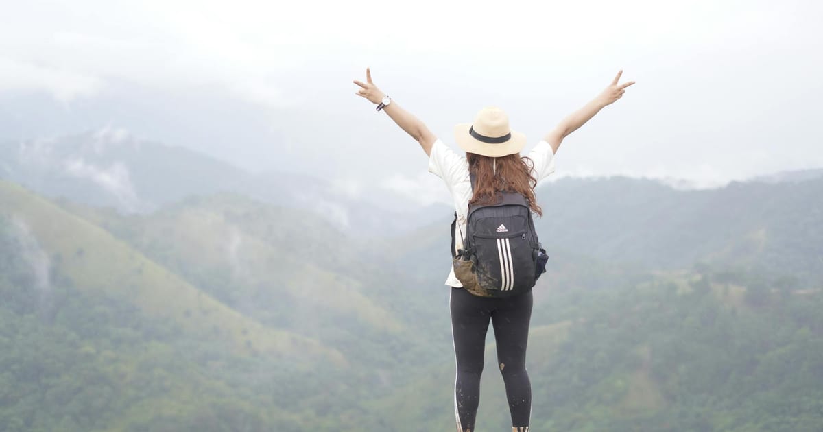 Mujer viajera con mochila contemplando un paisaje costero al atardecer